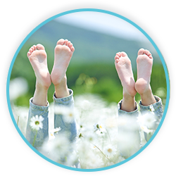 two children's feet sticking out of a field of daisies