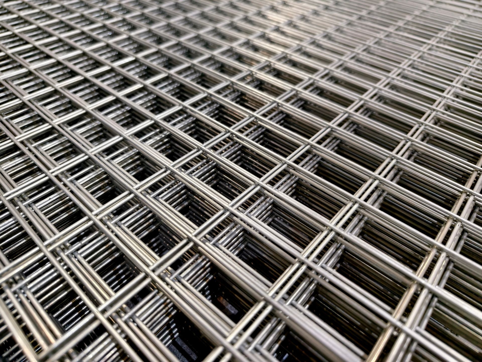 A close-up, angled view of industrial steel wire mesh with a repeating square grid pattern.