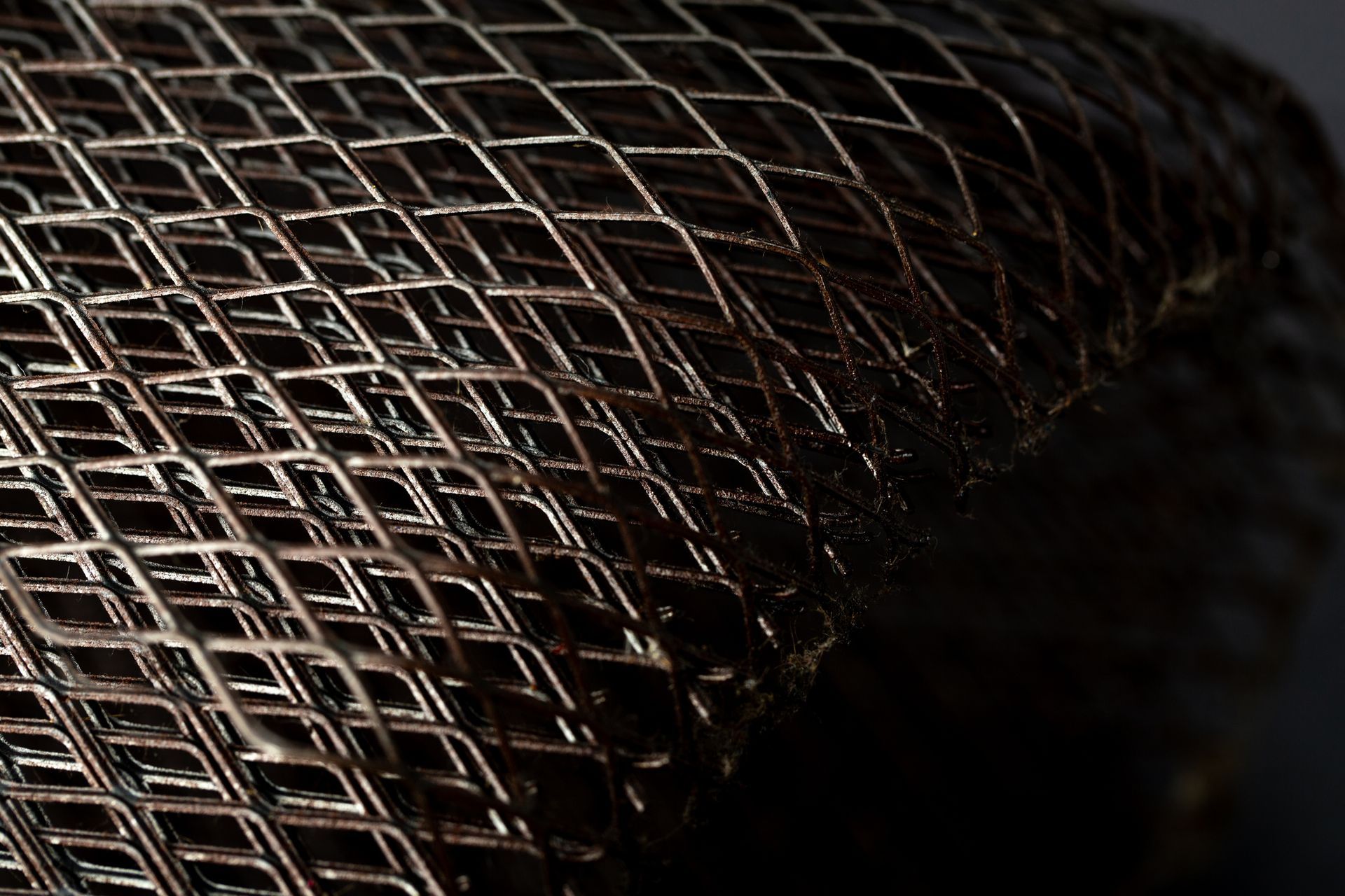 Metallic lattice with interlocking diagonal mesh in geometric pattern.