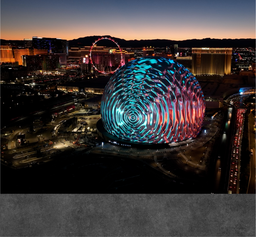 An aerial view of a city at night with a ferris wheel in the background