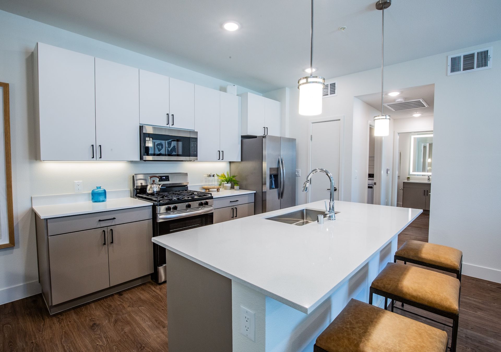 Modern kitchen with white and beige cabinets, stainless steel appliances, and a large island.
