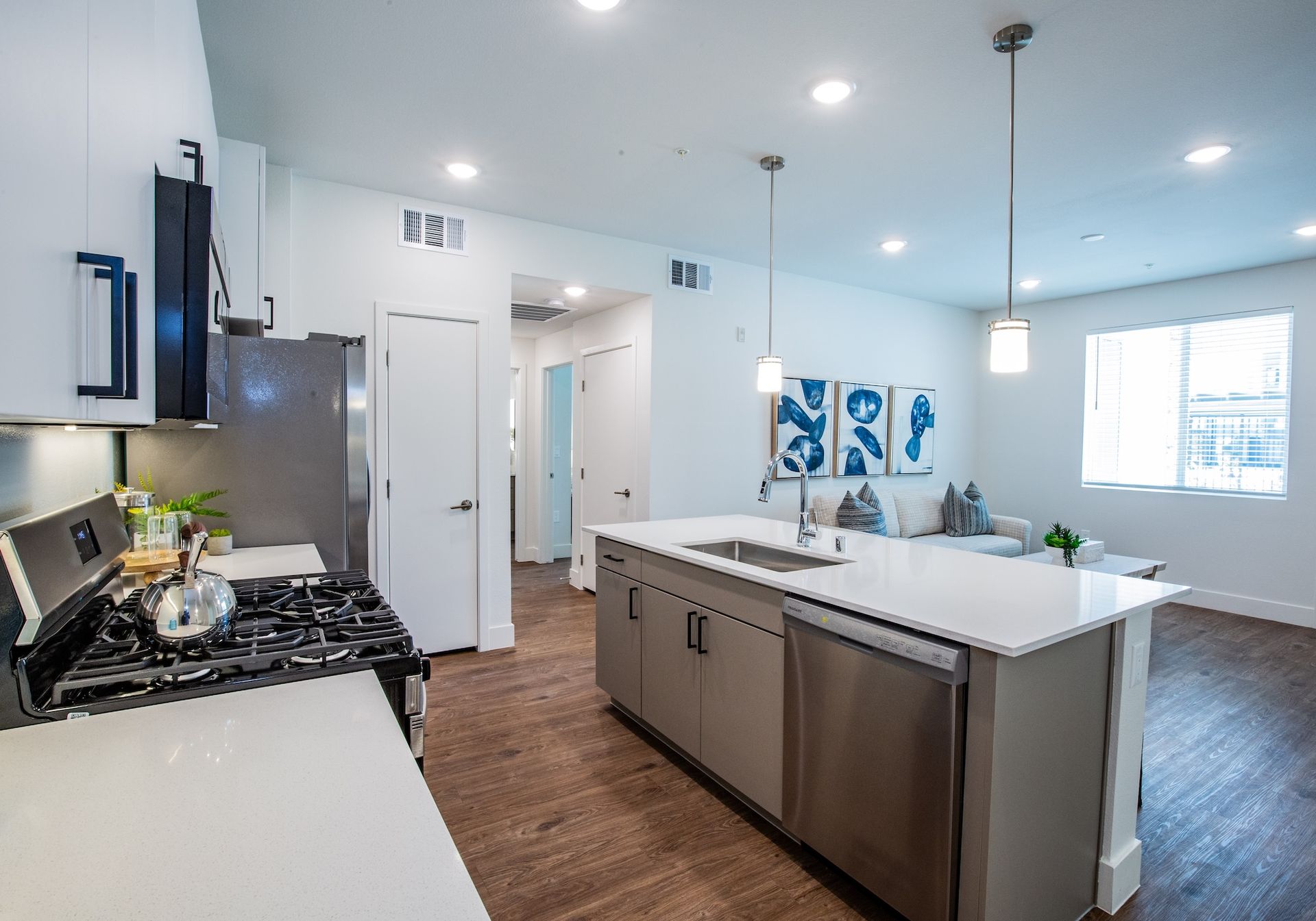 Modern kitchen with island, stainless steel appliances, and open layout to living area.