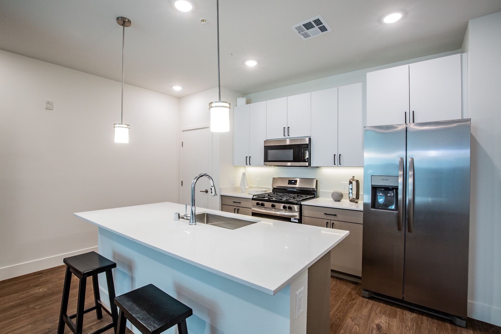 Modern kitchen with white cabinets, stainless steel appliances, and island with stools.