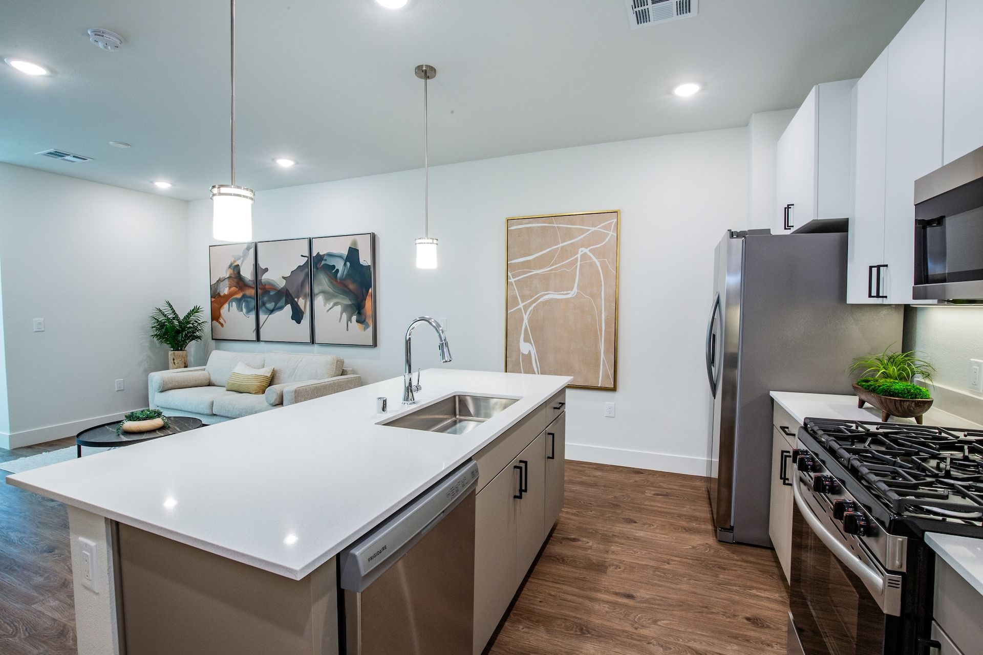 Modern kitchen with white countertops, stainless steel appliances, and island.