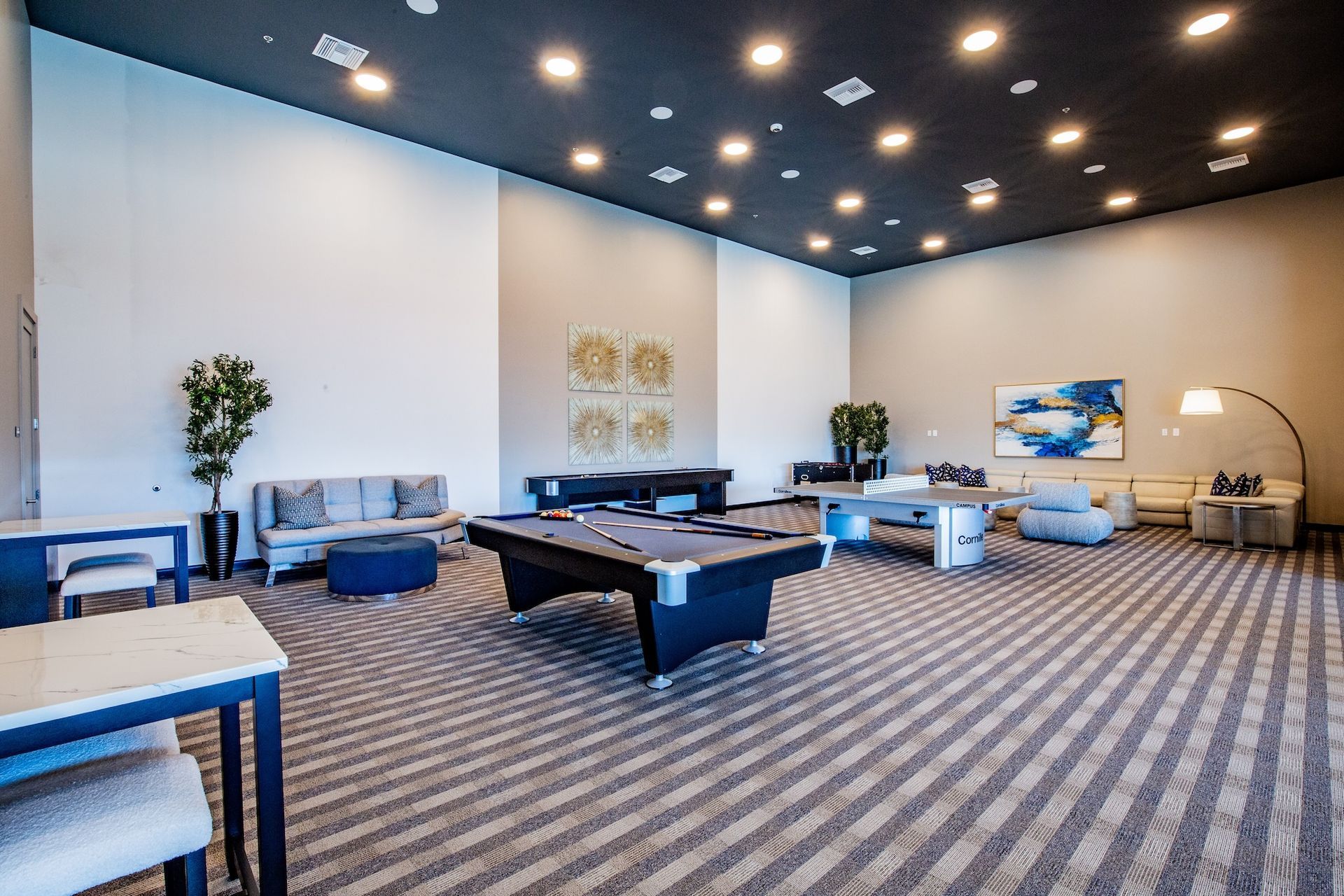 Spacious rec room with pool table, couches, tables, and art; gray and blue color scheme.