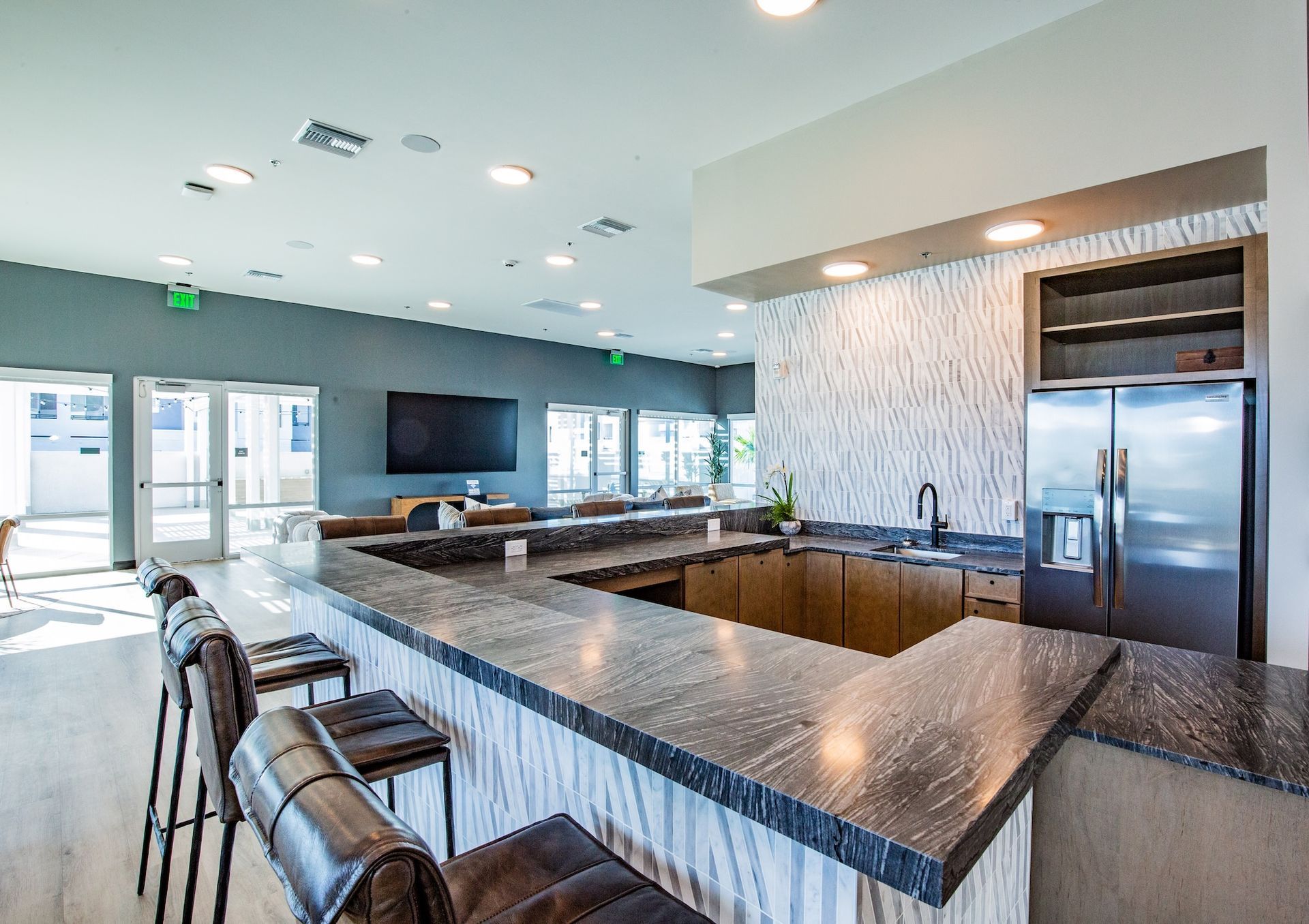 Interior lounge with a bar, stools, large TV, and a stainless steel refrigerator.