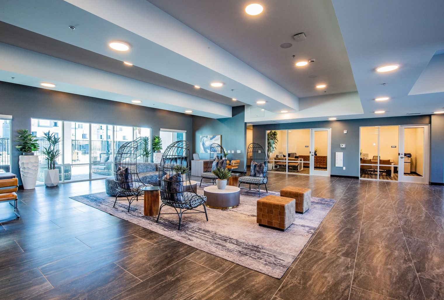 Lobby with seating, large windows, recessed lighting, and access to offices. Gray, blue, and brown tones.