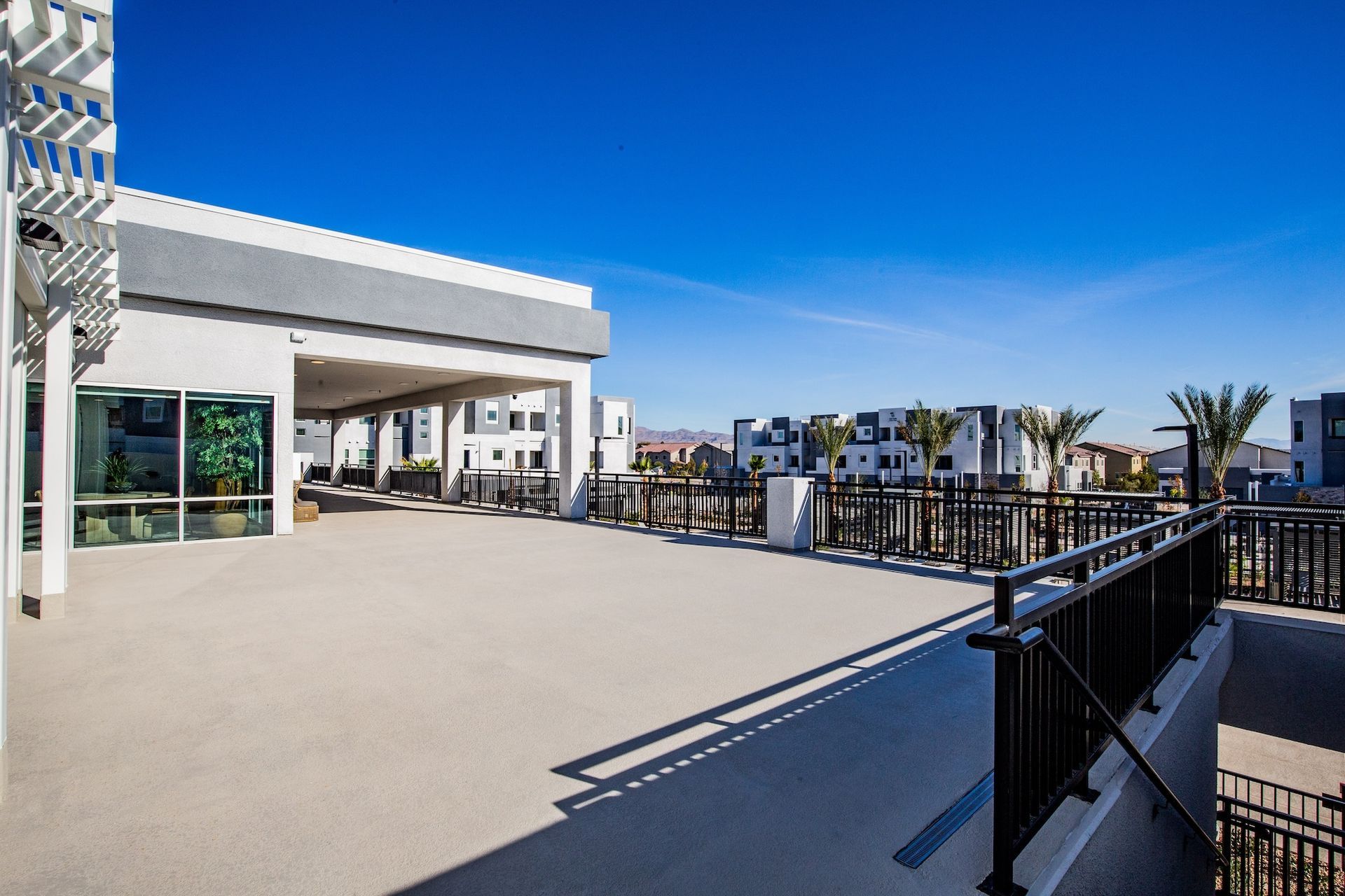 Rooftop patio with views of buildings, black railing, blue sky.