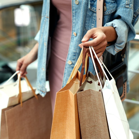 A woman in a denim jacket is holding a bunch of shopping bags