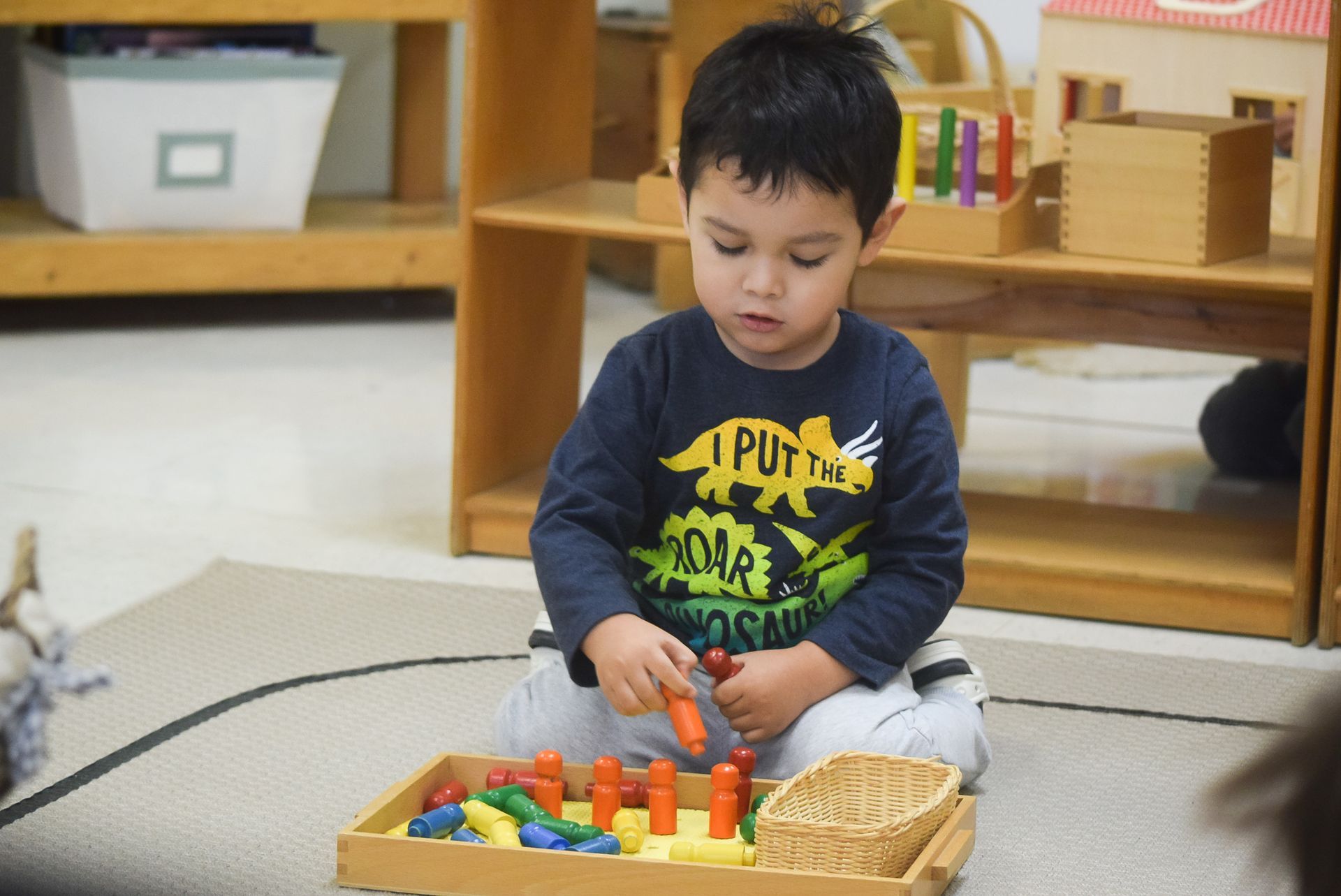 Boy playing with colorful wooden toys in a Montessori classroom setting.