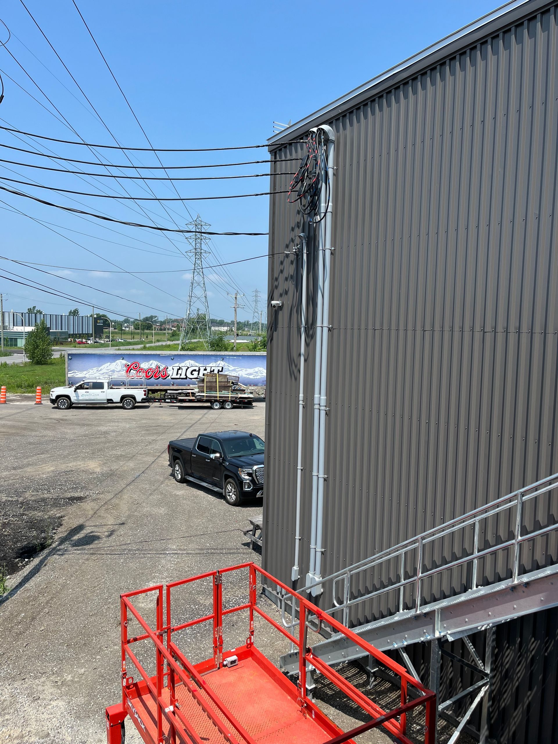 Un échafaudage rouge est posé à côté d'un bâtiment dans un parking.
