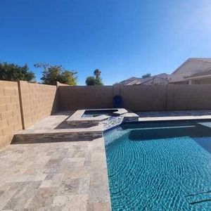 There is a large swimming pool in the backyard of a house.