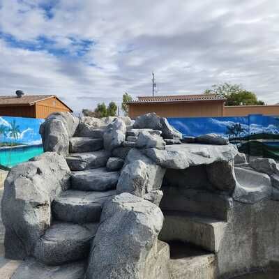 A large rock formation with stairs leading up to it next to a pool.