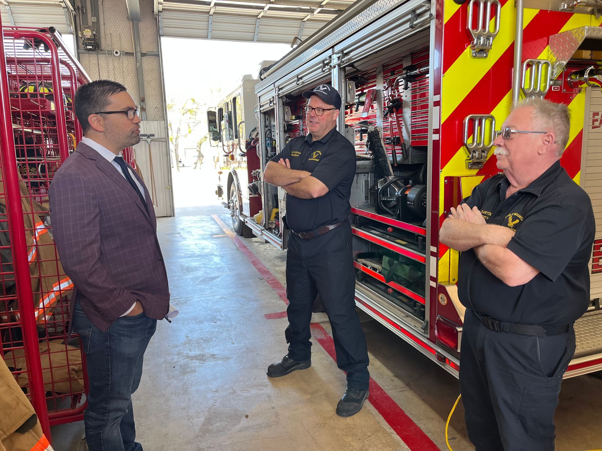 A group of men are standing in front of a fire truck.