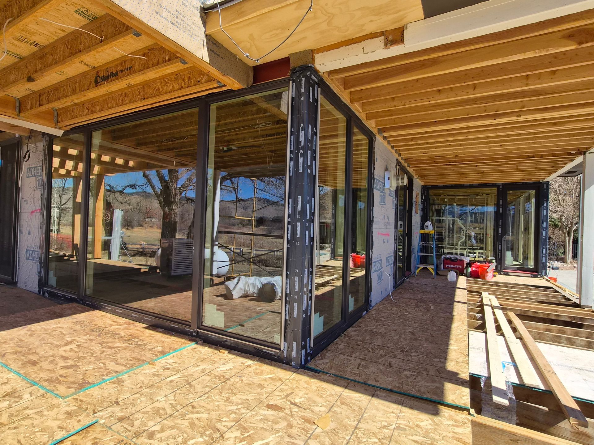 An exterior view of a construction site featuring a modern glass wall installation on a building under renovation.