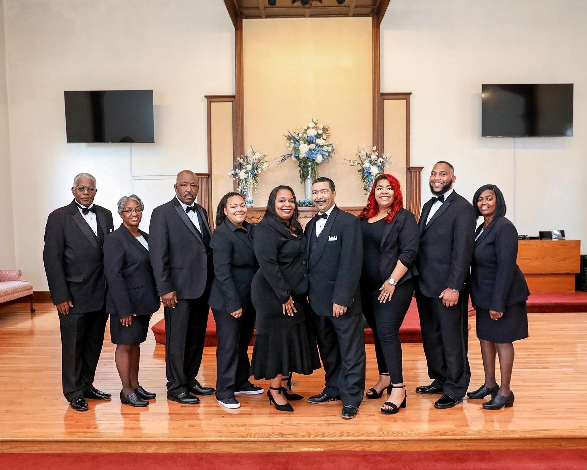 Group of people in formal attire posing on a church stage.