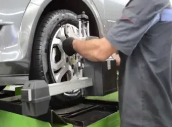 Mecânico usando uma máquina de balanceamento de pneus em uma roda de carro prata em uma garagem.