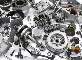 Diversas peças metálicas de motores e transmissões espalhadas sobre um fundo branco.
