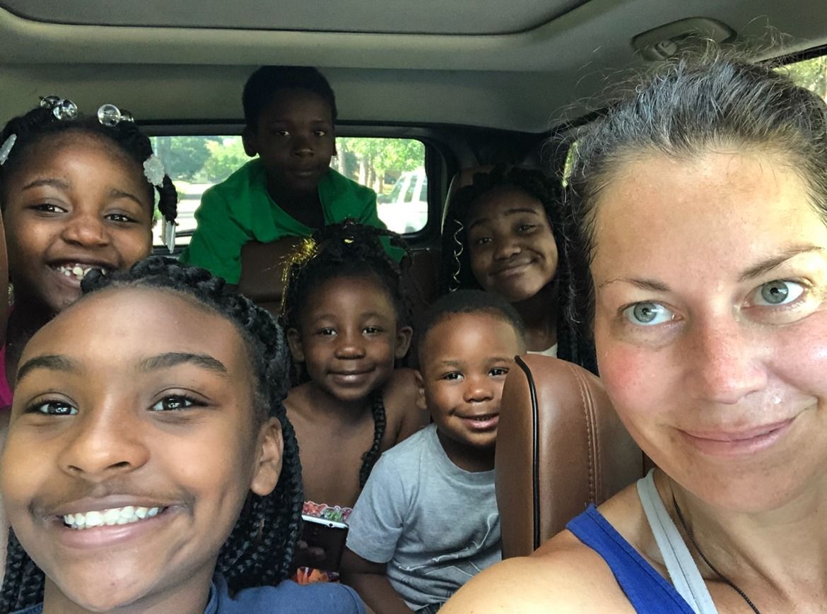 A group of people smiling together for a selfie inside a vehicle.