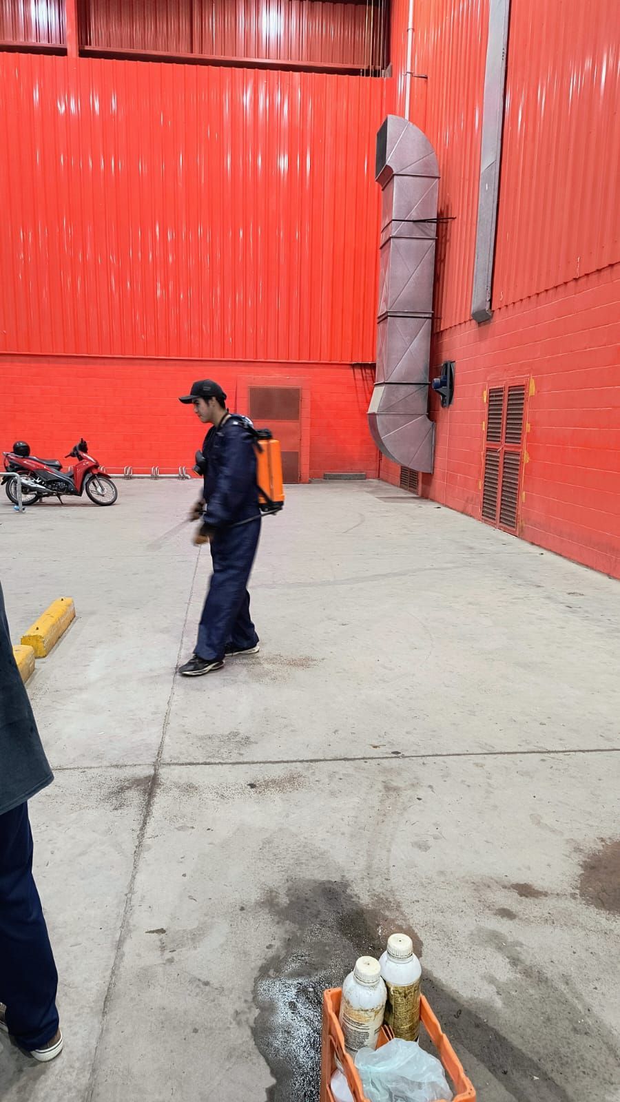 Un hombre está rociando productos químicos en el suelo de un almacén.