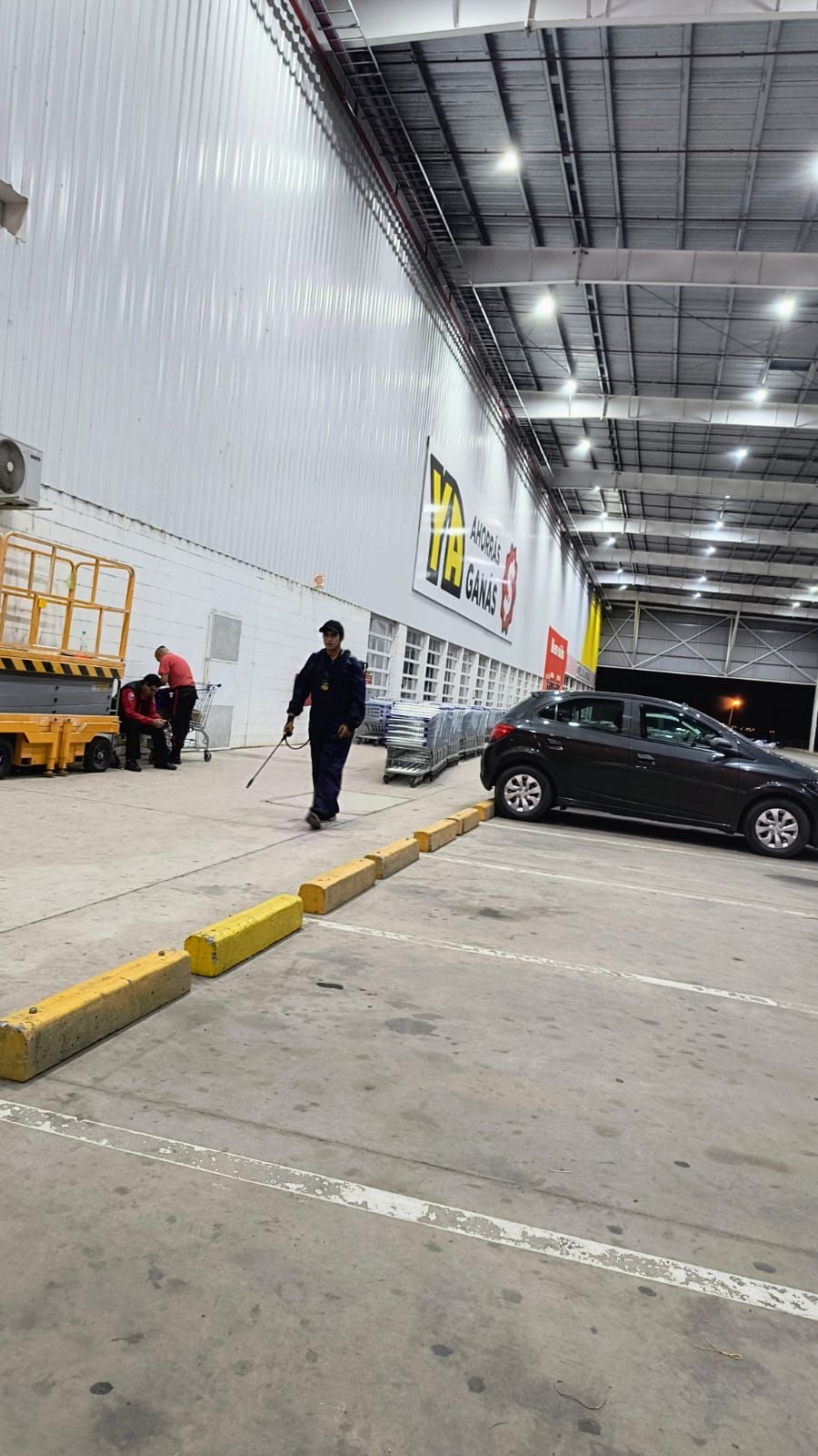 Un hombre está rociando un estacionamiento con una manguera.