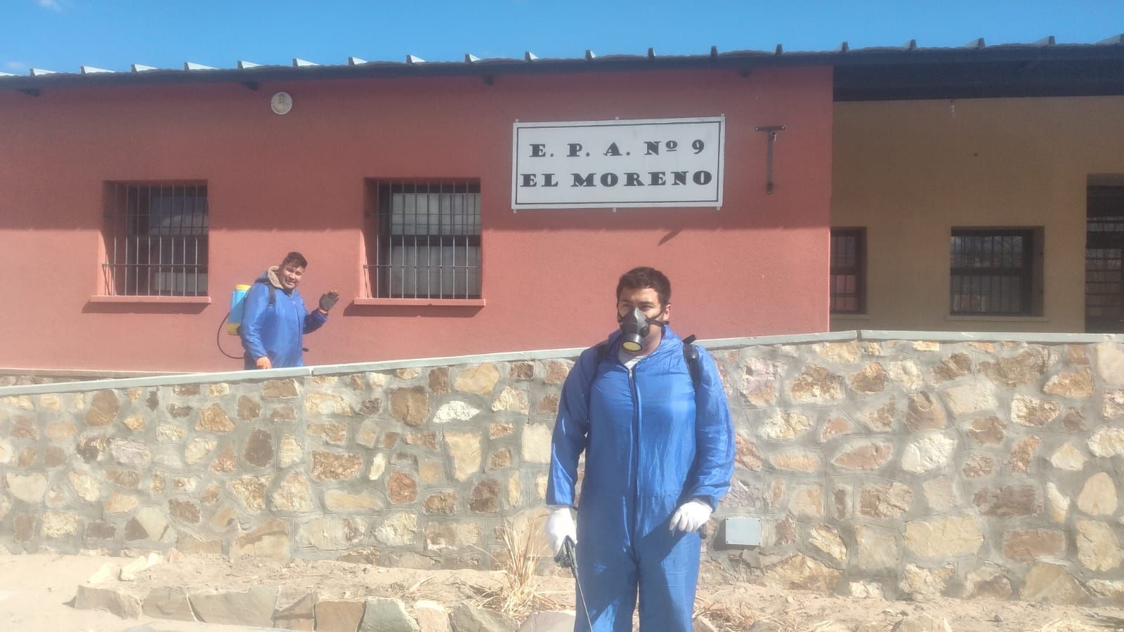 Un hombre con un mono azul está parado frente a un edificio que dice El Moreno.