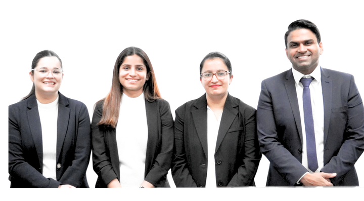 Four professionals in suits smiling at the camera.