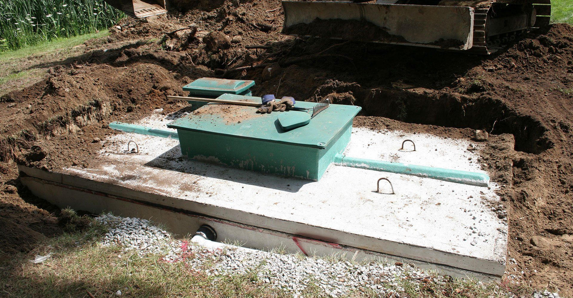 Septic tank installation site, concrete tank in excavated ground, green lids.