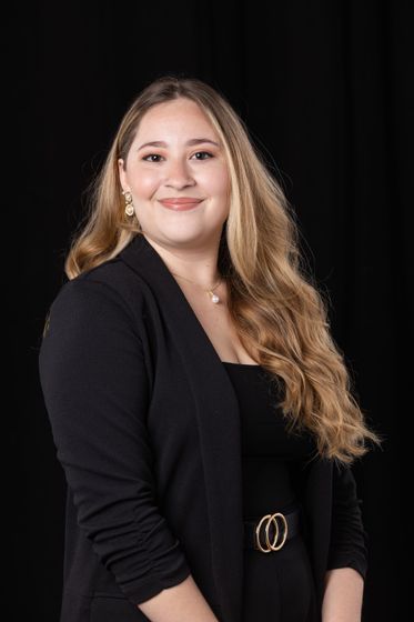 Portrait of a smiling woman in a black outfit against a dark background