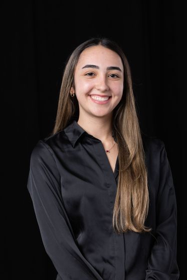 Smiling person in a black shirt against a dark background
