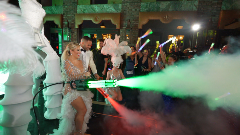 LED-lit performer entertaining a cheering crowd at a purple-lit party