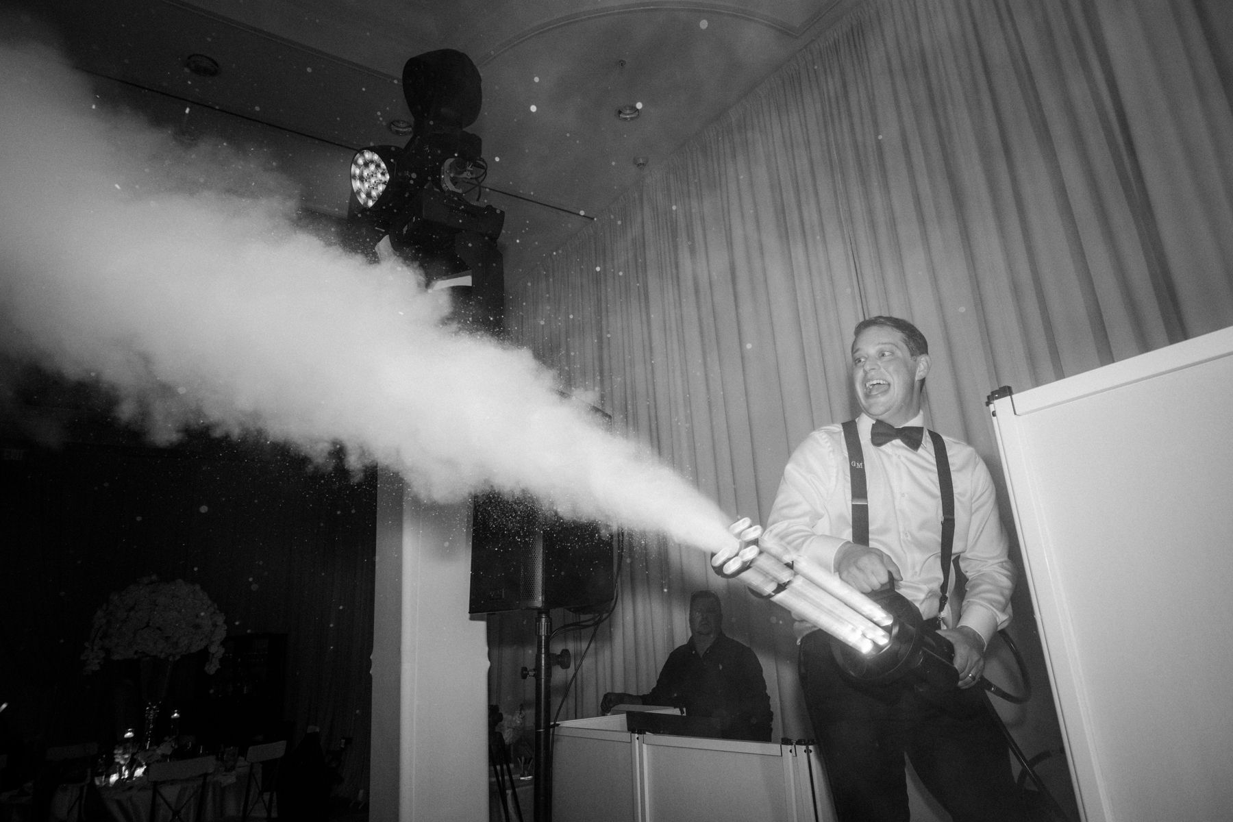 Person using a fire extinguisher sprays foam in a smoky room near a curtain.