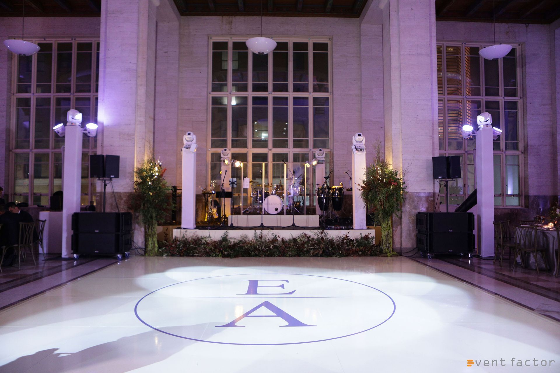 Elegant wedding reception stage with white floral arrangements, candles, and a glossy aisle backdrop