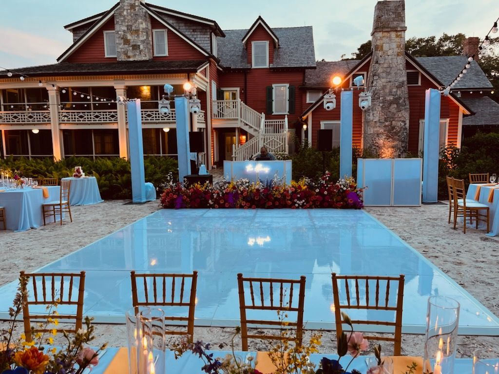 Elegant gold-and-lavender wedding reception hall with a lit dance floor and stage backdrop reading “Emilia & Julius”