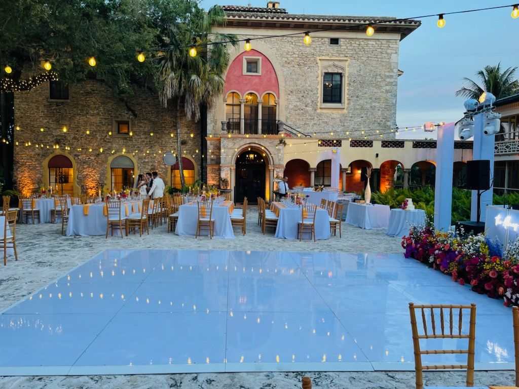 Elegant wedding reception stage with pink-purple drapery, floral arch, and monogrammed dance floor