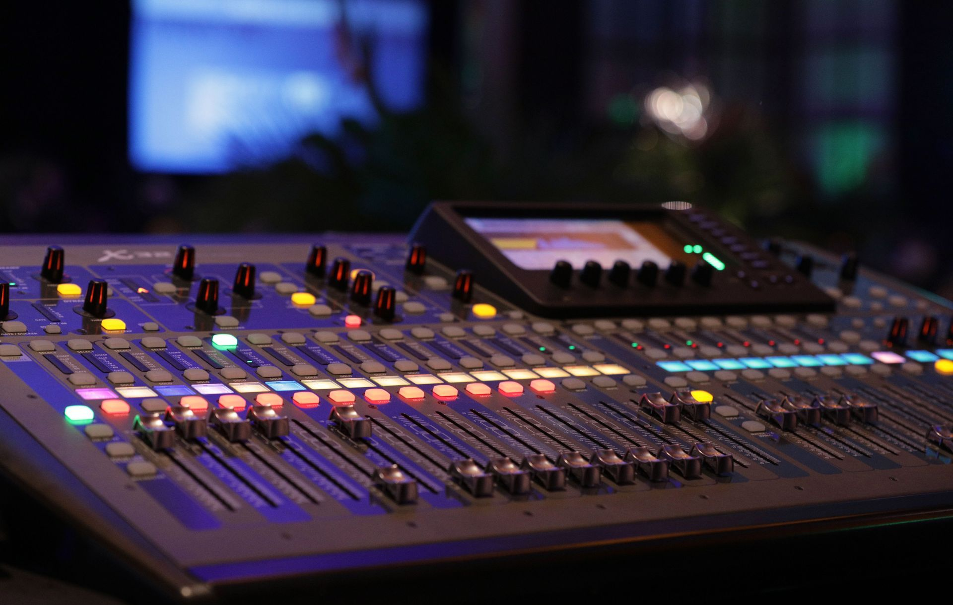 Sound mixing console with glowing controls in a dim studio