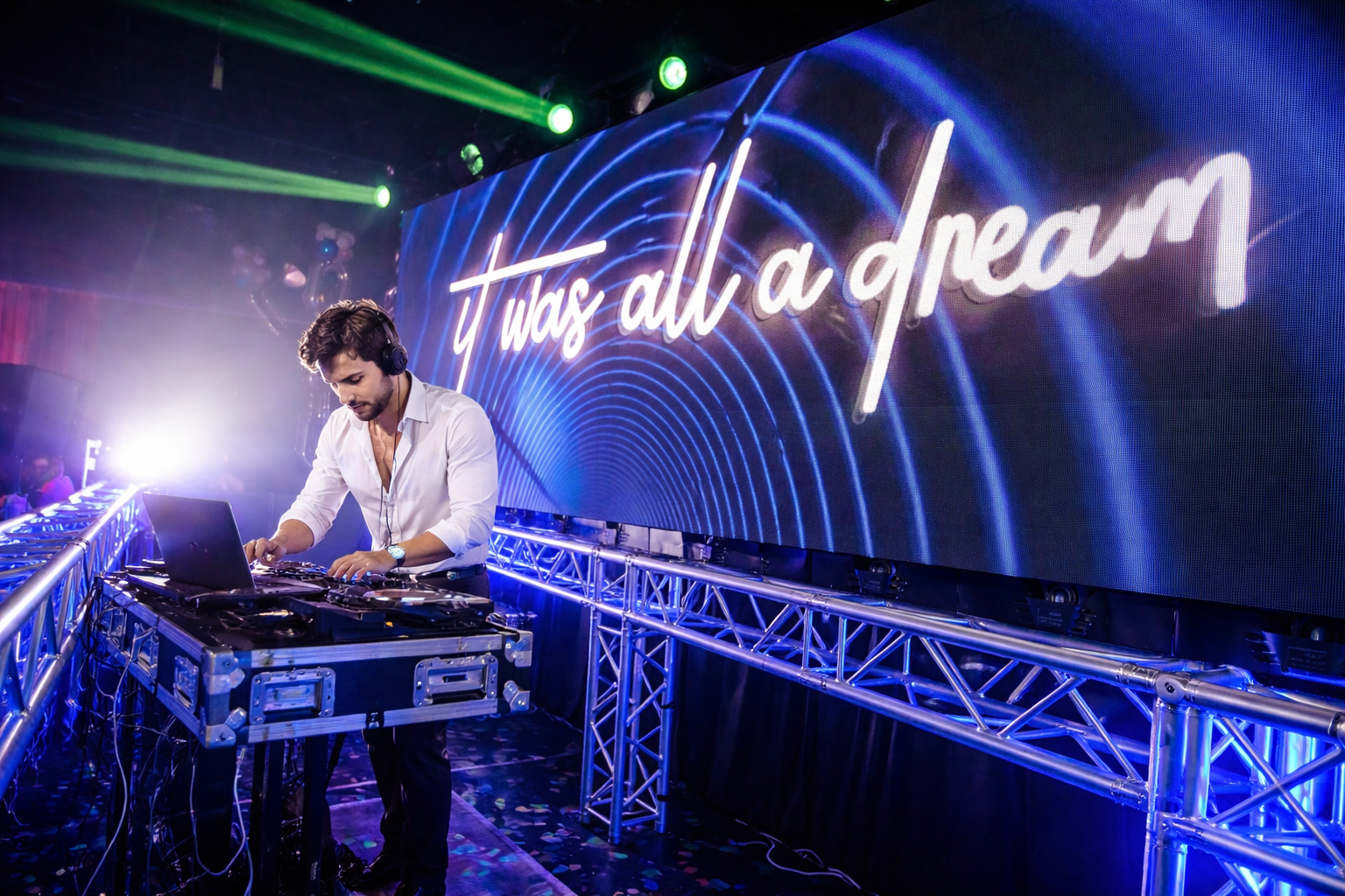 DJ performing on stage under blue and purple lights, with “just all a dream” glowing behind him.