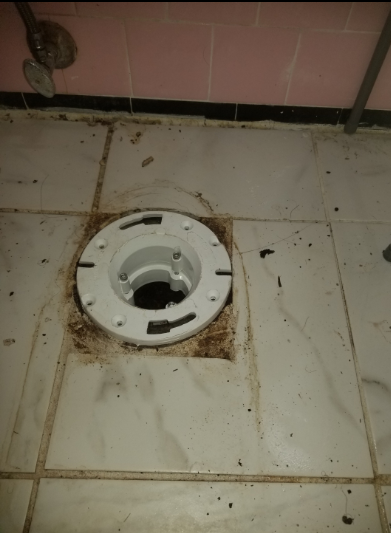 A toilet flange on a tiled floor in a bathroom