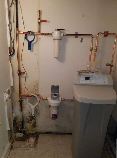 A bathroom with a sink and a water filter on the wall.