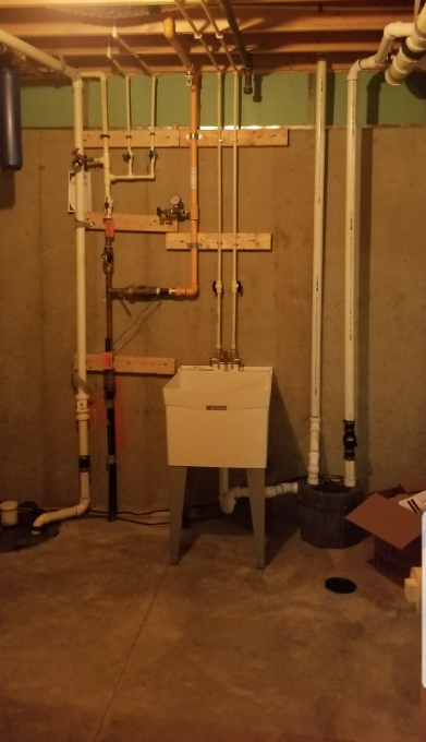 A basement with lots of pipes and a sink