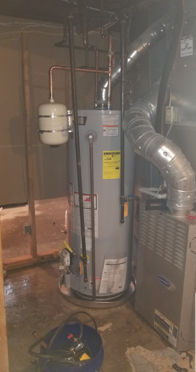 A water heater is sitting in a basement next to a furnace.