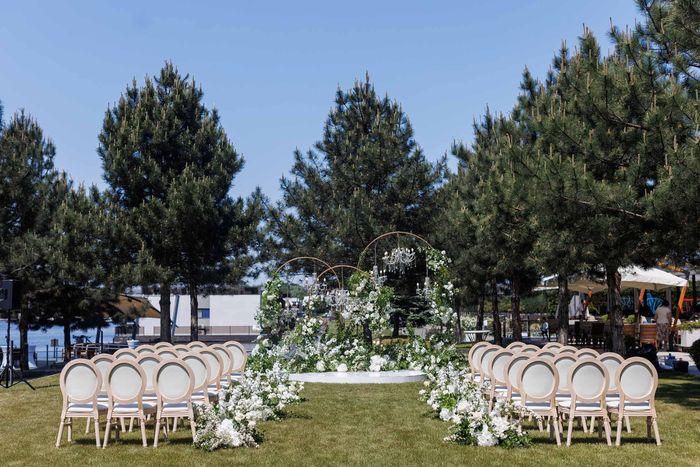 A wedding ceremony is taking place in a field surrounded by trees