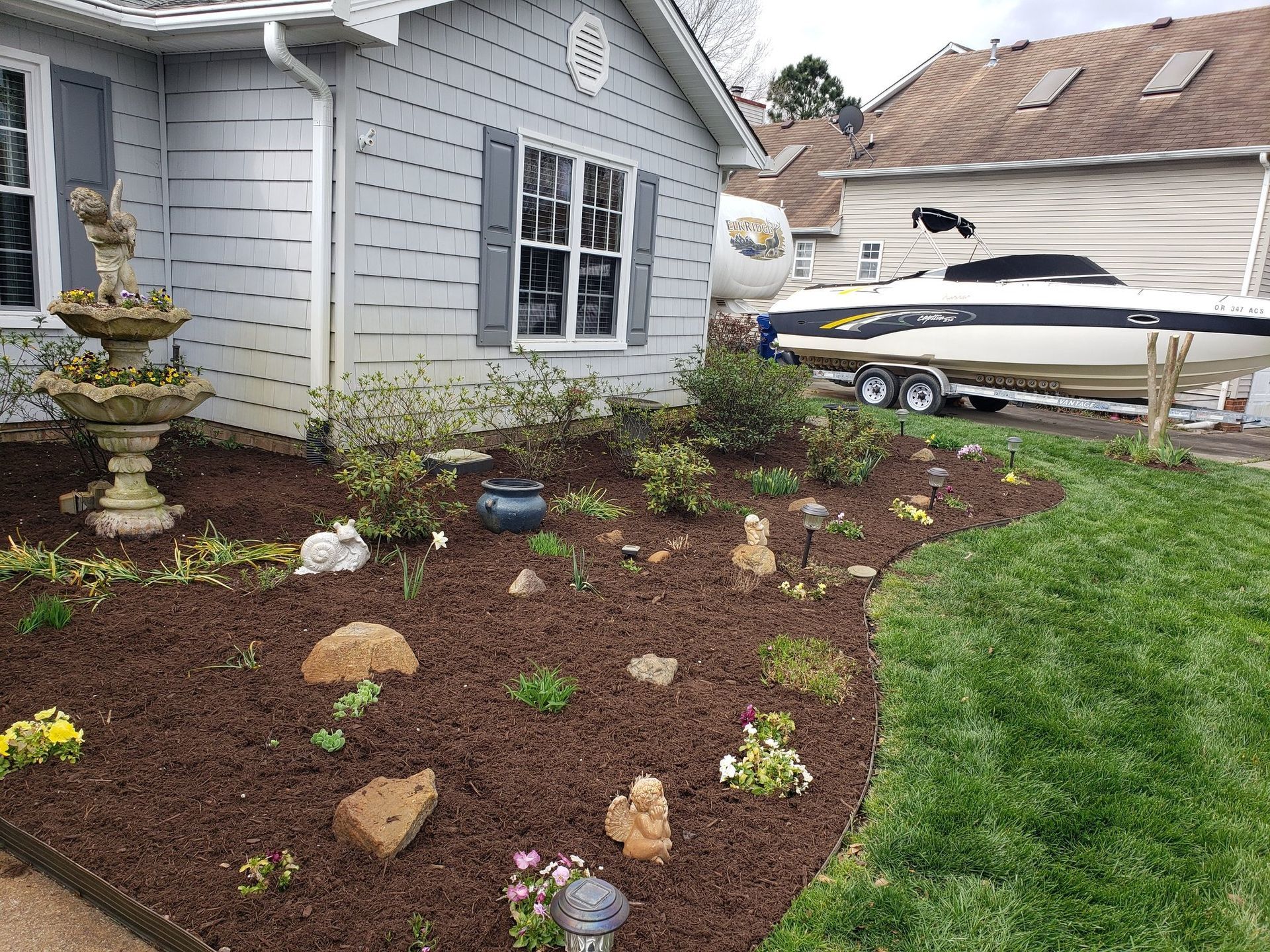 House with a landscaped yard and a boat parked in the driveway.
