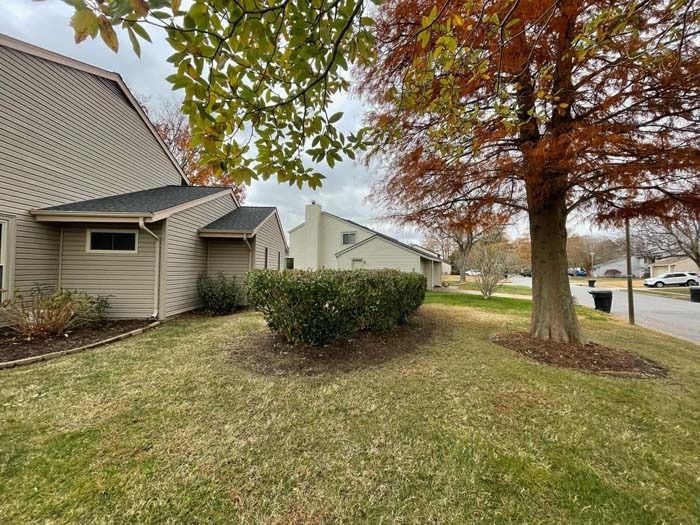 Houses and trees with fall foliage; a grassy yard. Overcast sky.