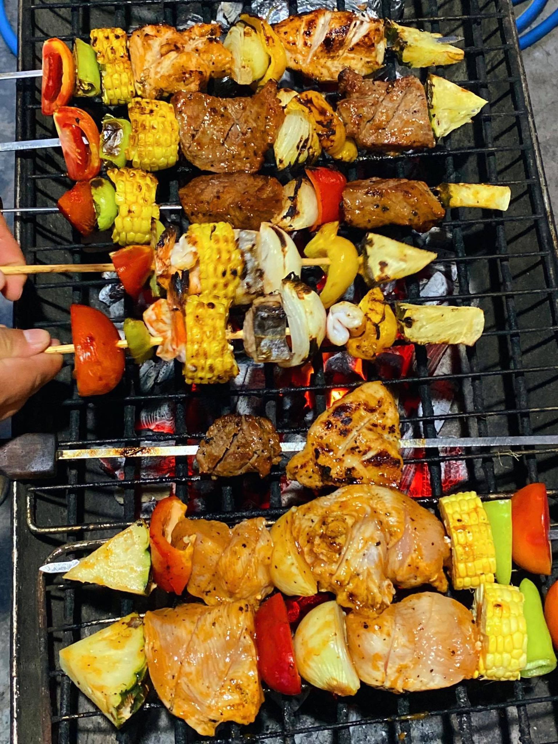 Skewers of grilled meat and vegetables on a charcoal grill.