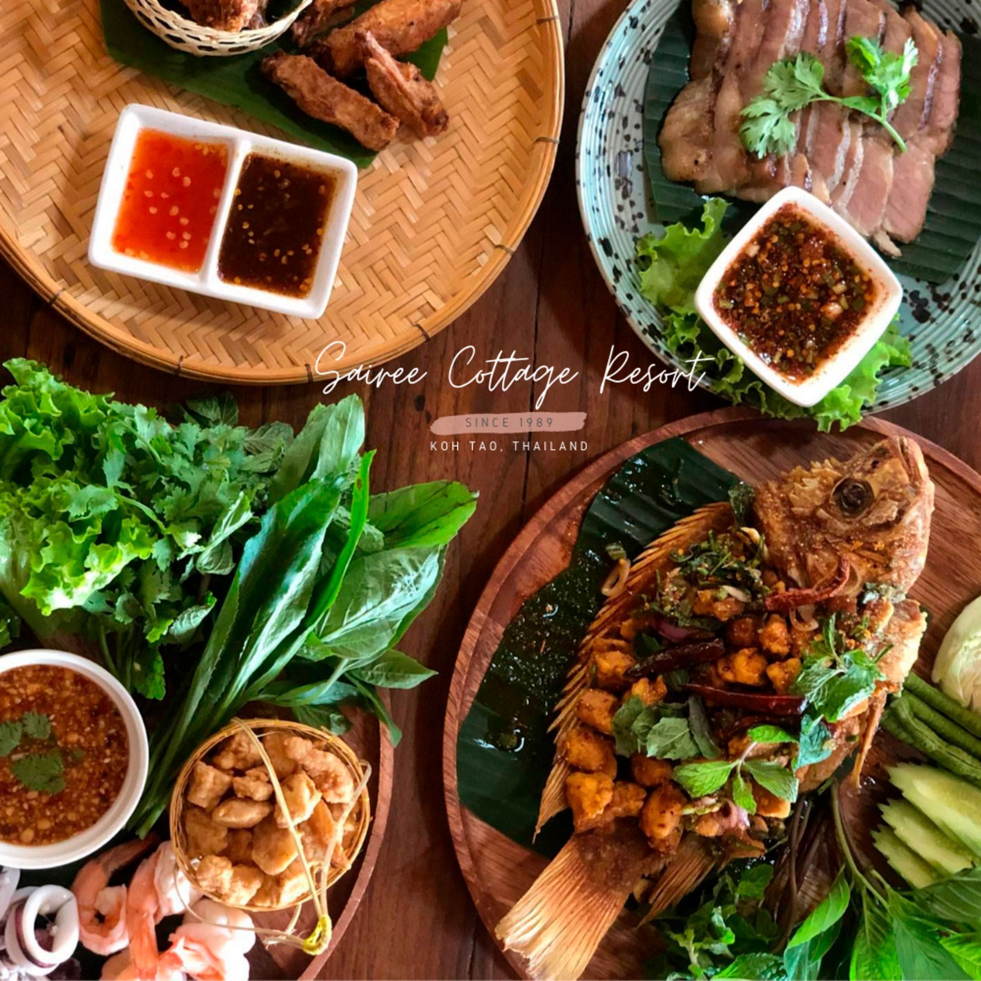 Overhead shot of Thai food spread, with fried fish, grilled pork, and dipping sauces.