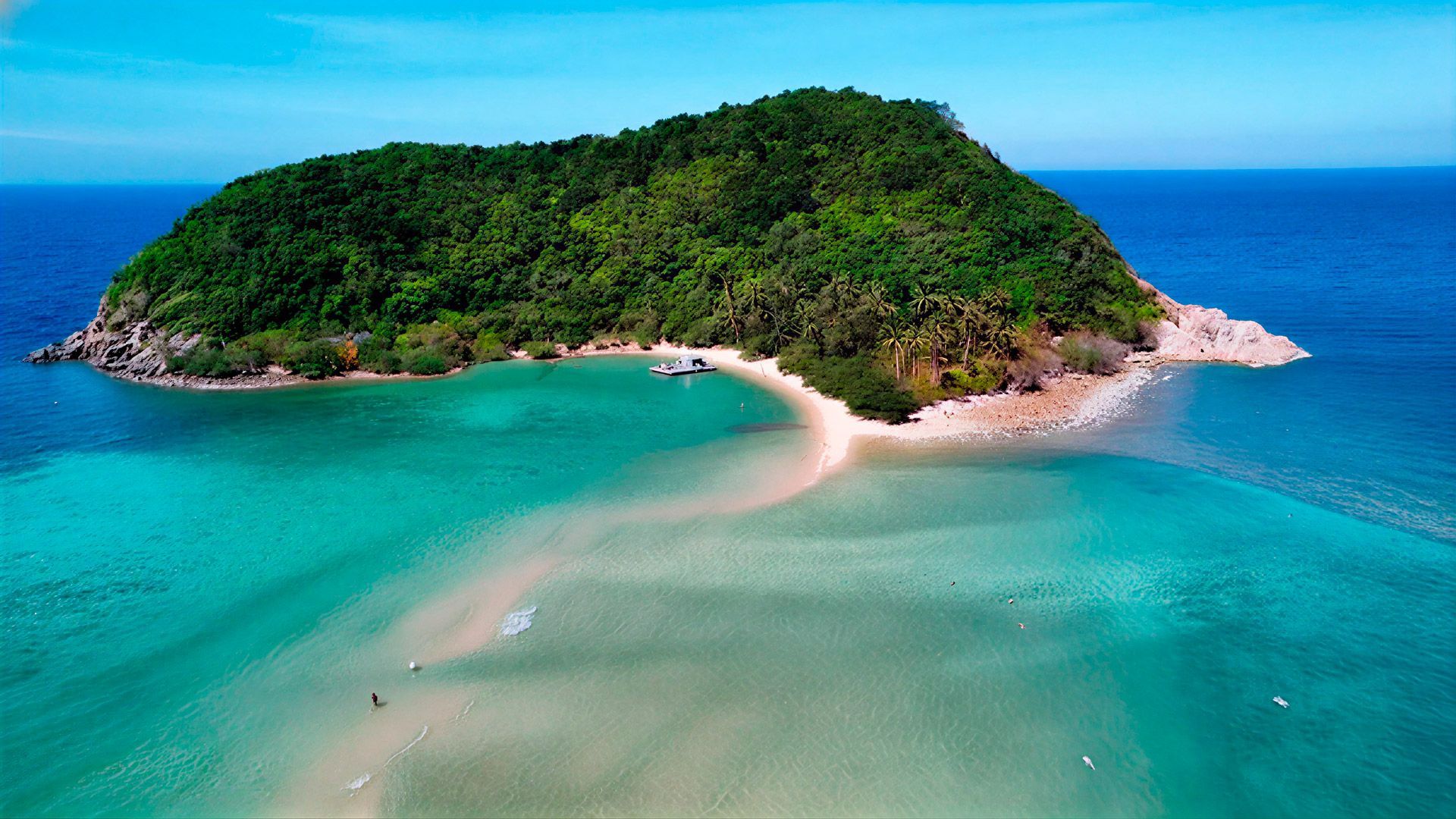 Island with lush green vegetation, white sand beach, and turquoise water.