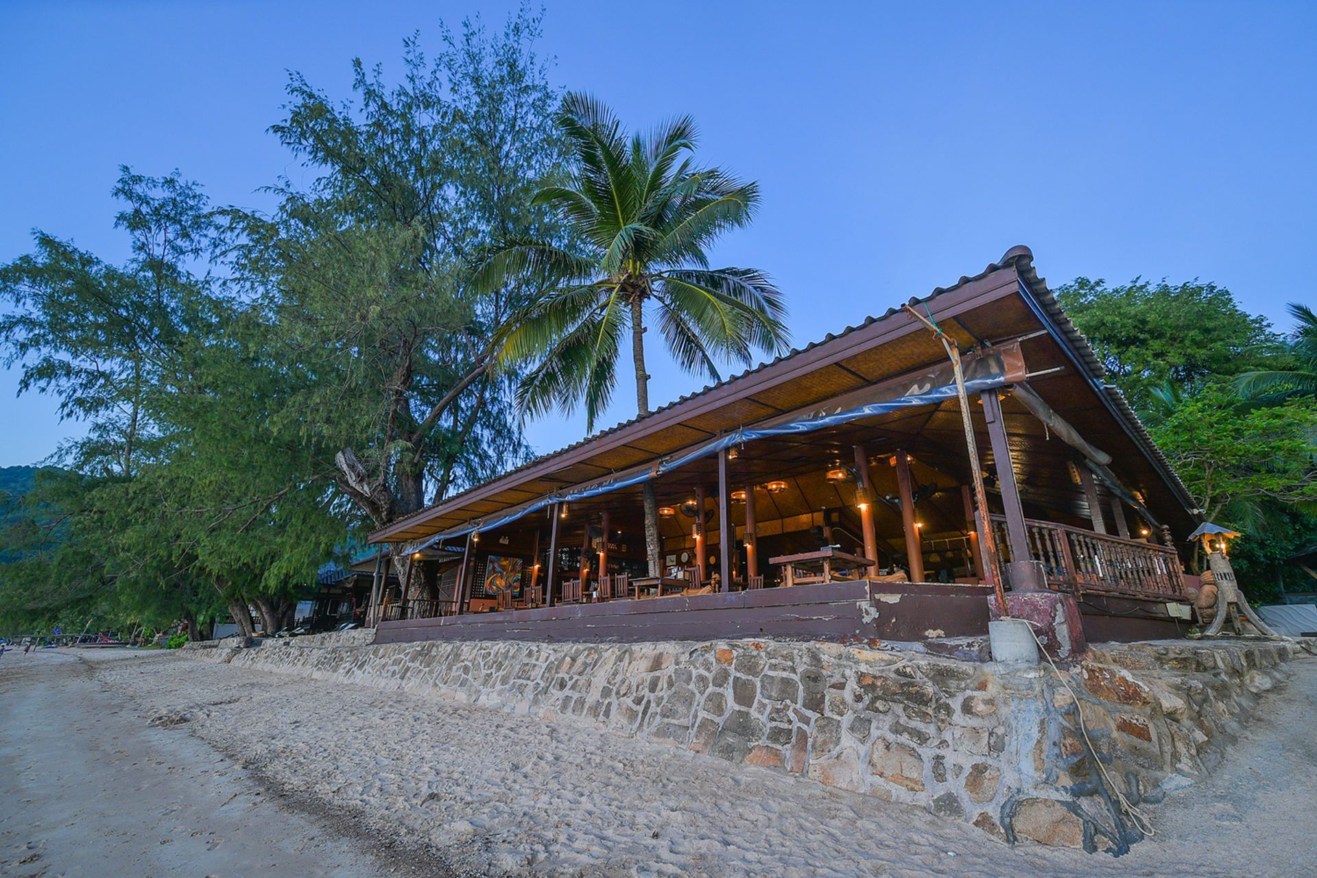 Wooden beachfront restaurant at dusk.
