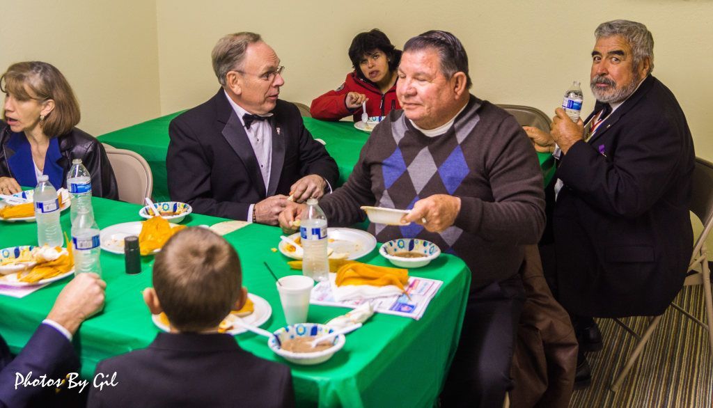Five people are seated at tables covered with bright green cloths.
