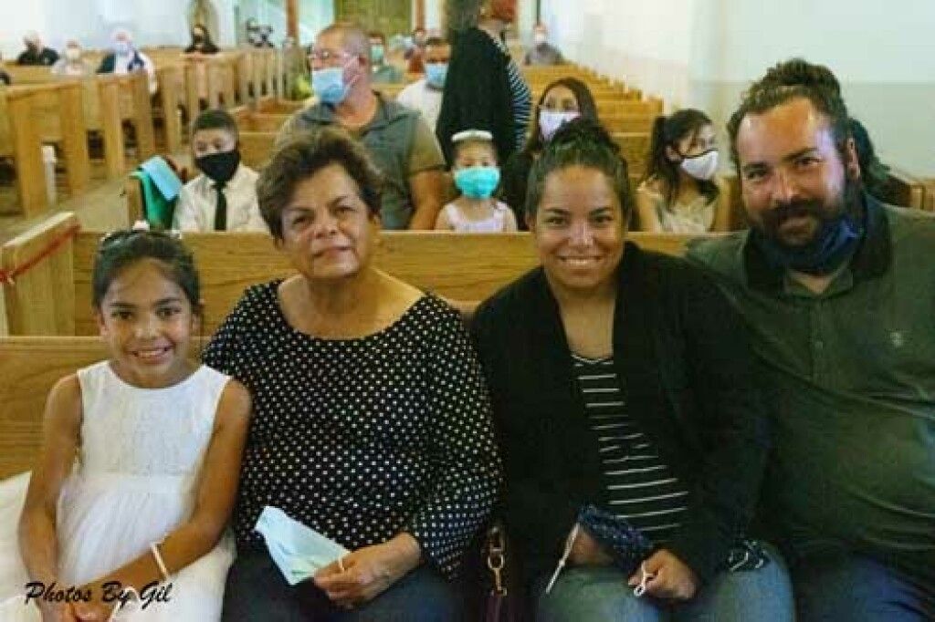 A family of four sits smiling in a church pew. 